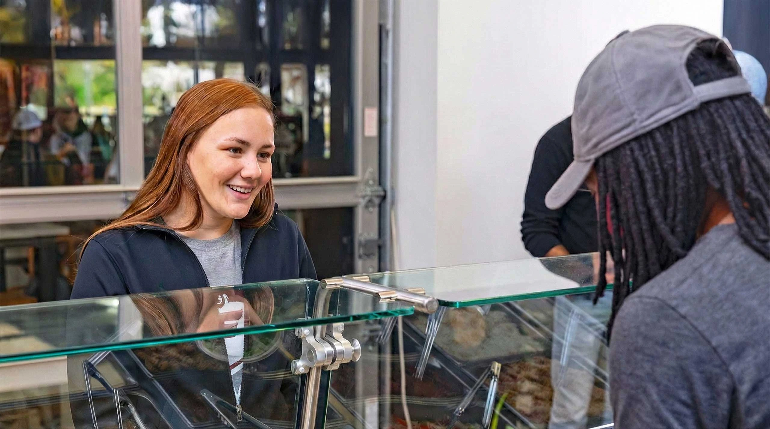 Student smiling at employee while waiting at serving line